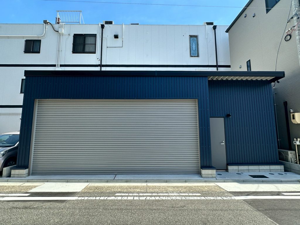 ネイビーブルー外壁が映えるおしゃれなガレージ施工事例｜電動シャッター付き車庫