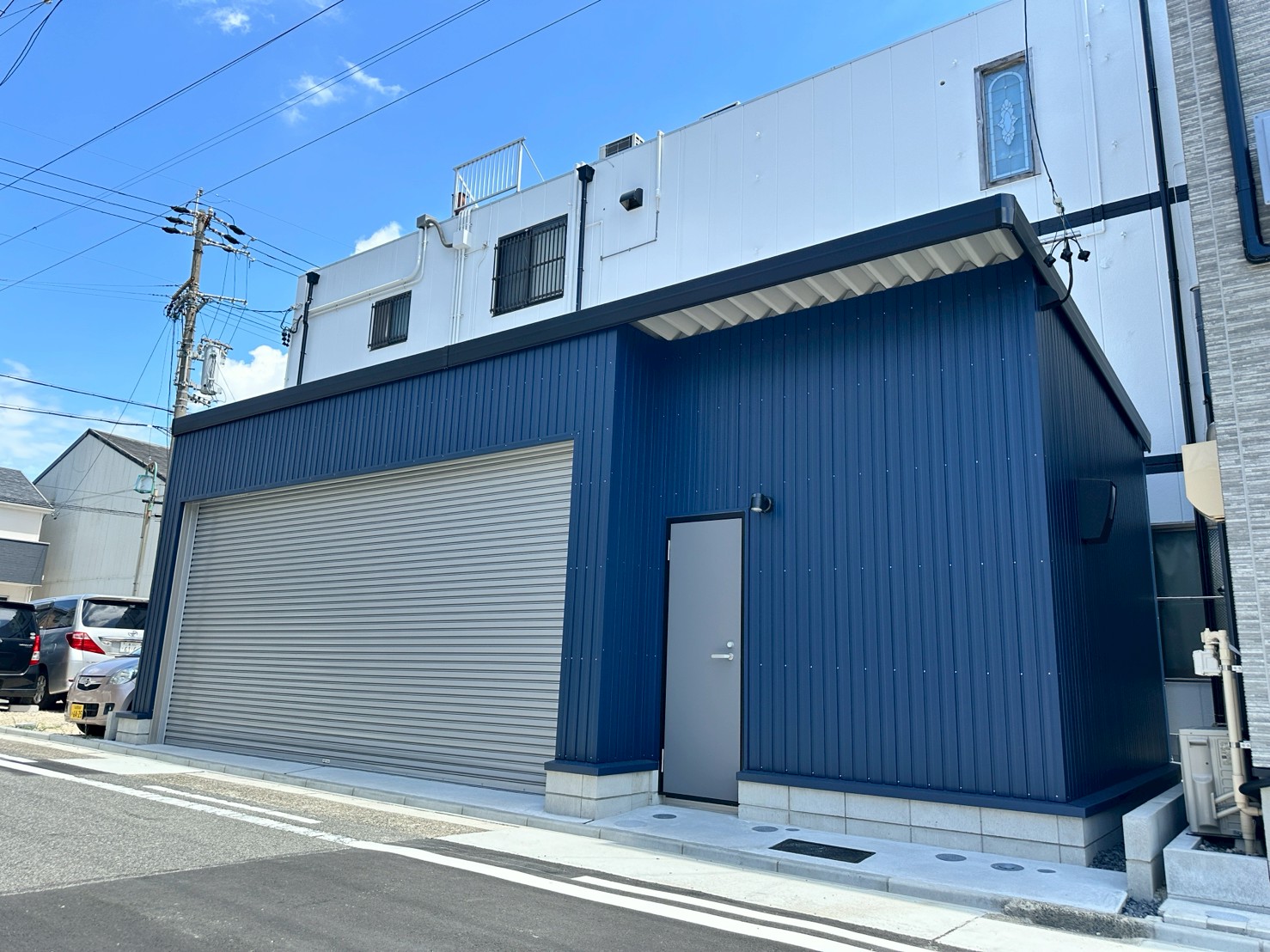 ネイビーブルー外壁が映えるおしゃれなガレージ施工事例｜電動シャッター付き車庫