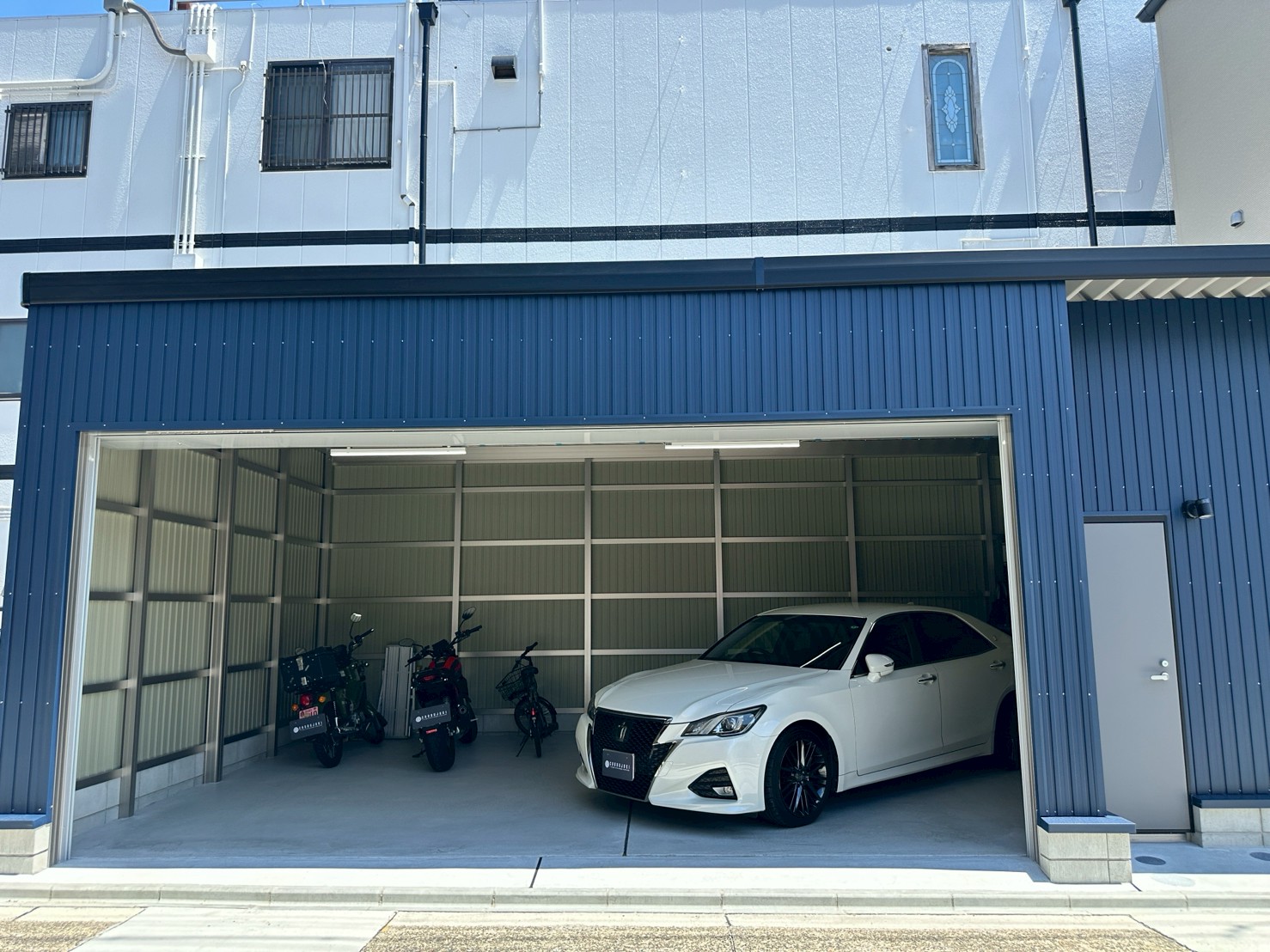 ネイビーブルー外壁が映えるおしゃれなガレージ施工事例｜電動シャッター付き車庫
