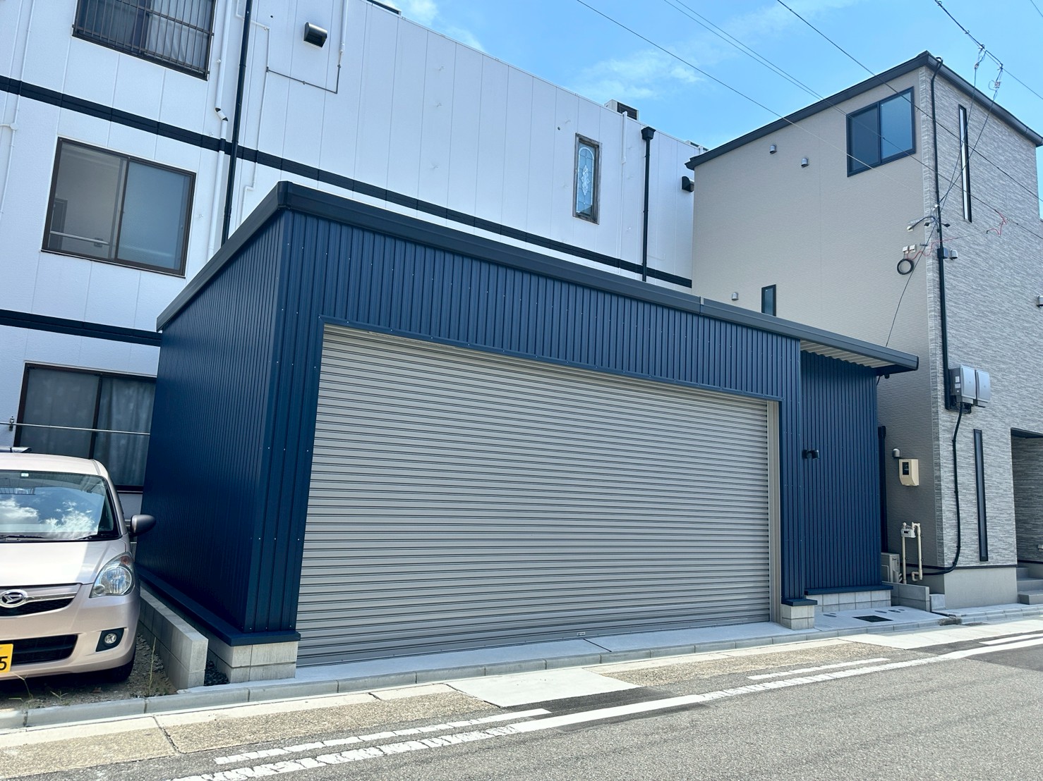 ネイビーブルー外壁が映えるおしゃれなガレージ施工事例｜電動シャッター付き車庫